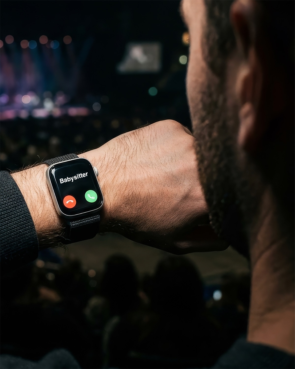 A smartwatch showing an incoming call from the babysitter during a concert